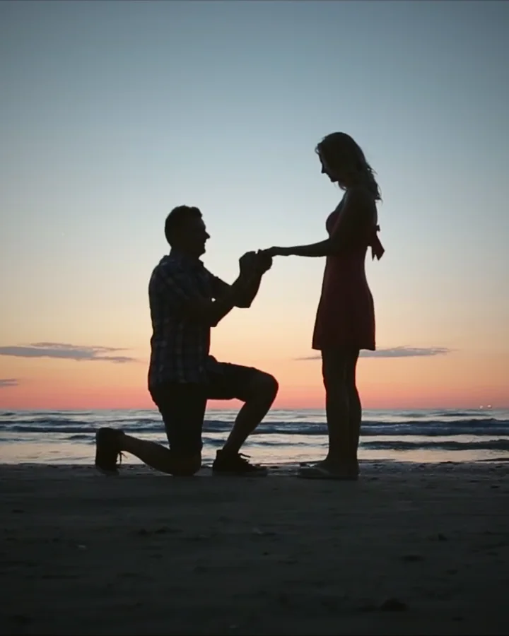 Pedida de mano al atardecer en la playa, la pareja a contraluz