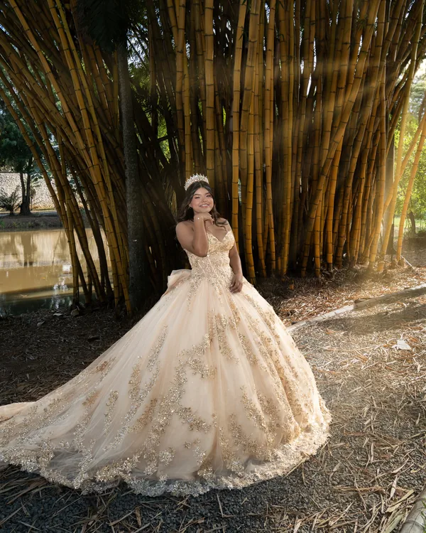 Quinceañera de cuerpo entero frente a un bosque de bambú, con rayos de sol entre las cañas