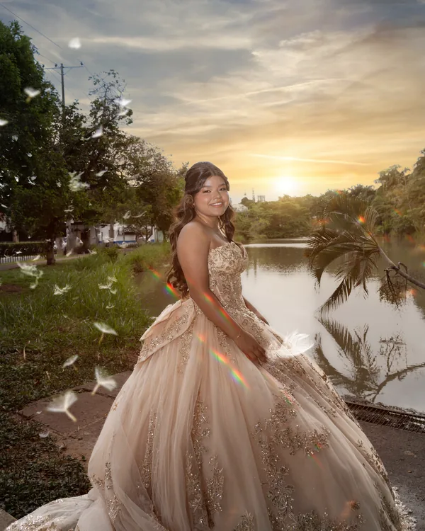 Quinceañera junto a un lago al atardecer, con el sol detrás de los árboles