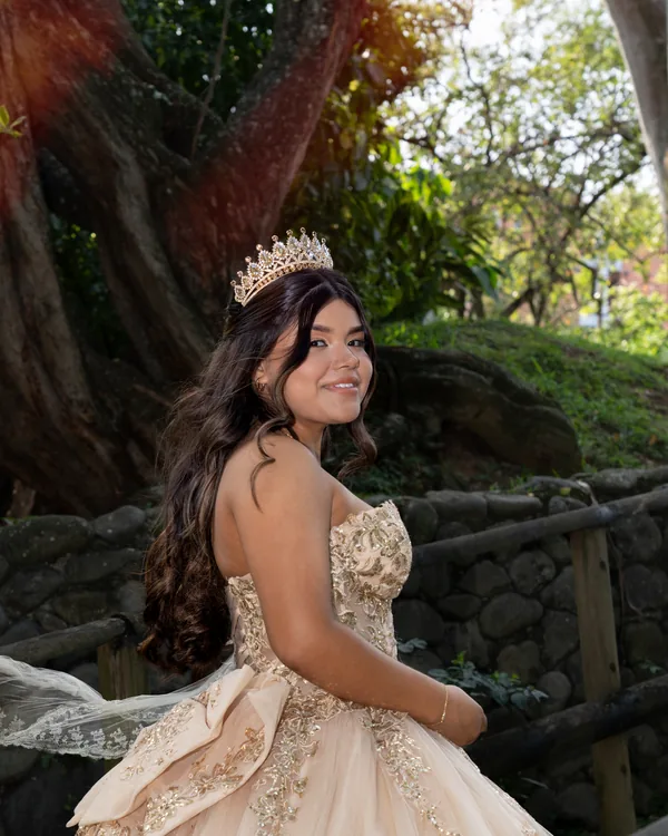 Quinceañera con tiara mirando por encima del hombro, con el moño del vestido y el velo