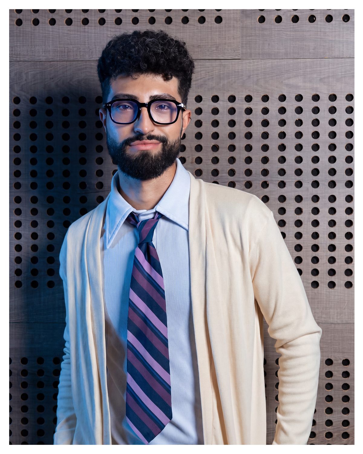 Modelo con camisa azul, corbata a rayas y abrigo claro