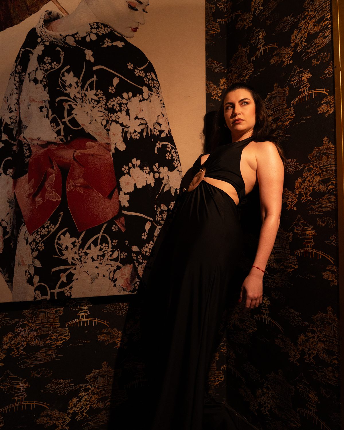 Modelo con vestido negro frente a un mural japonés en el restaurante