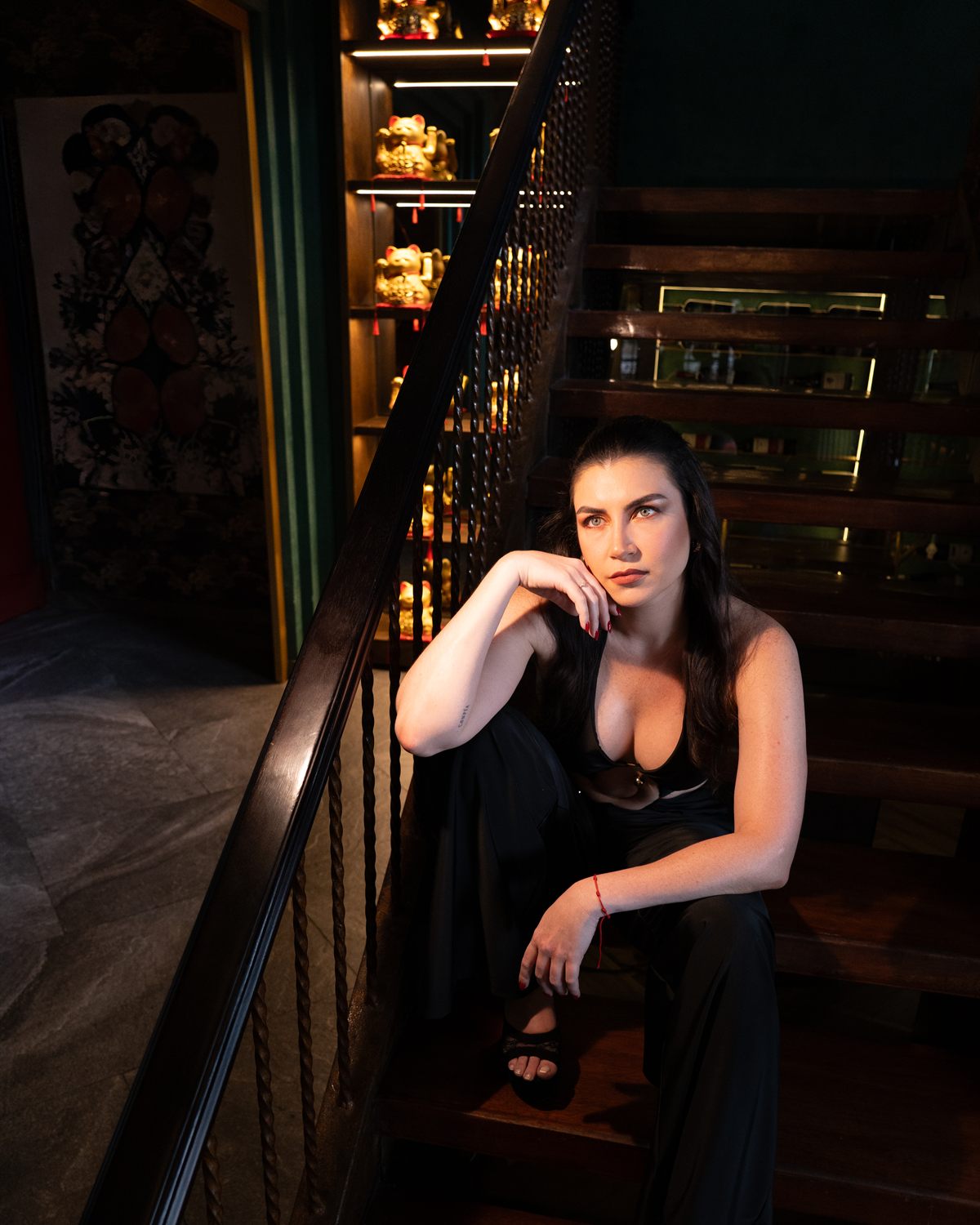 Modelo sentada en la escalera del restaurante con vestido negro