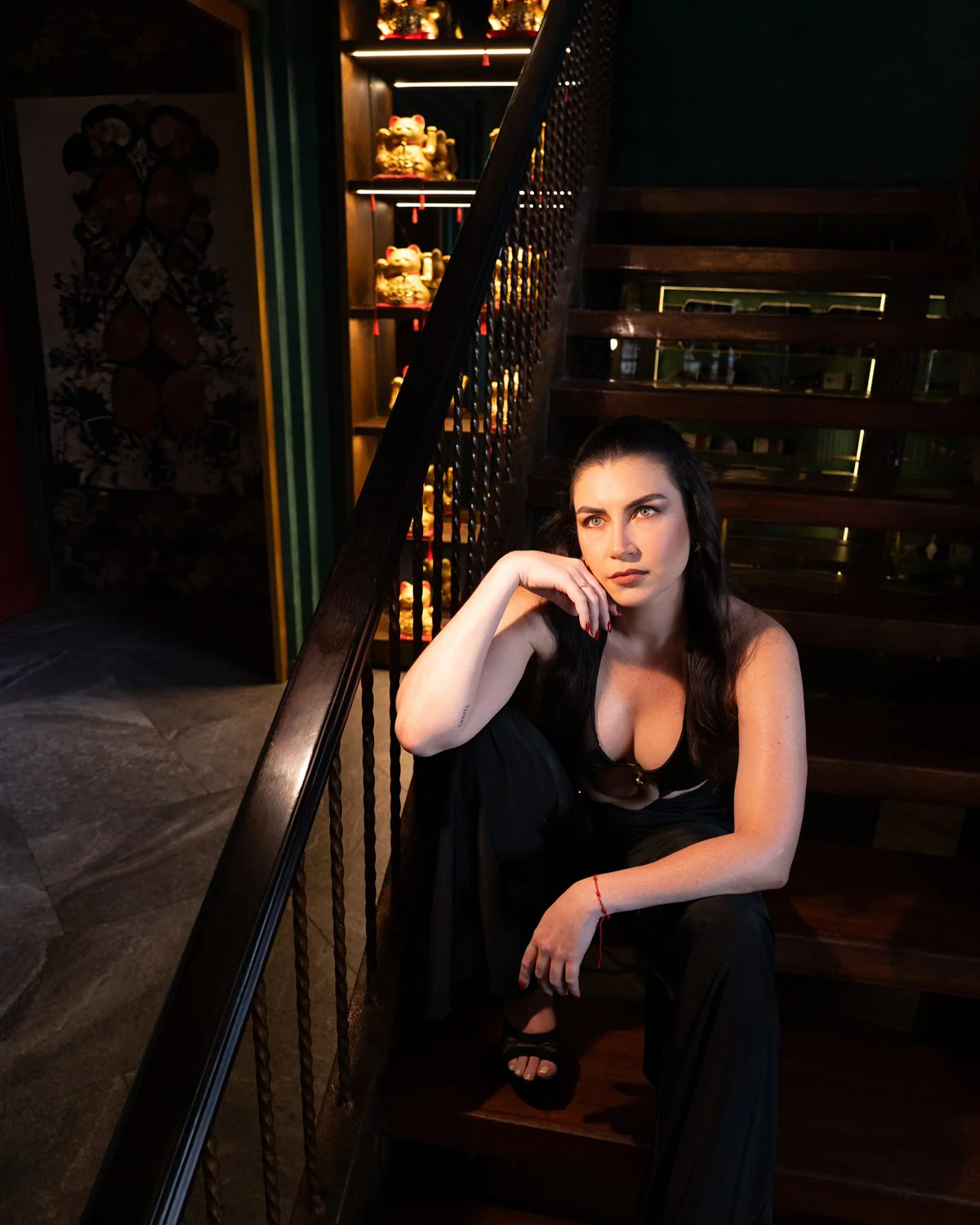 Modelo sentada en la escalera del restaurante con vestido negro