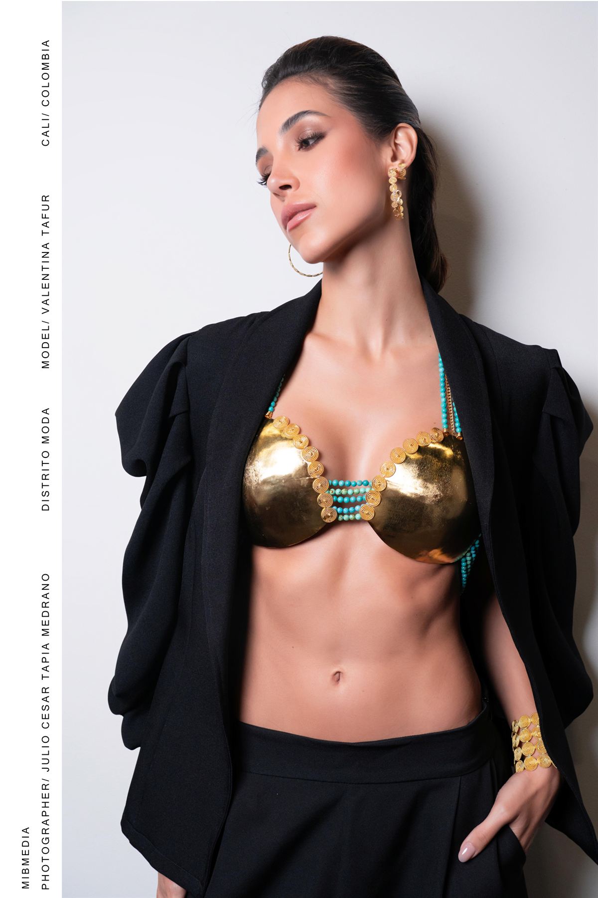 Modelo con pectoral dorado de filigrana y turquesas, con blazer negro sobre los hombros
