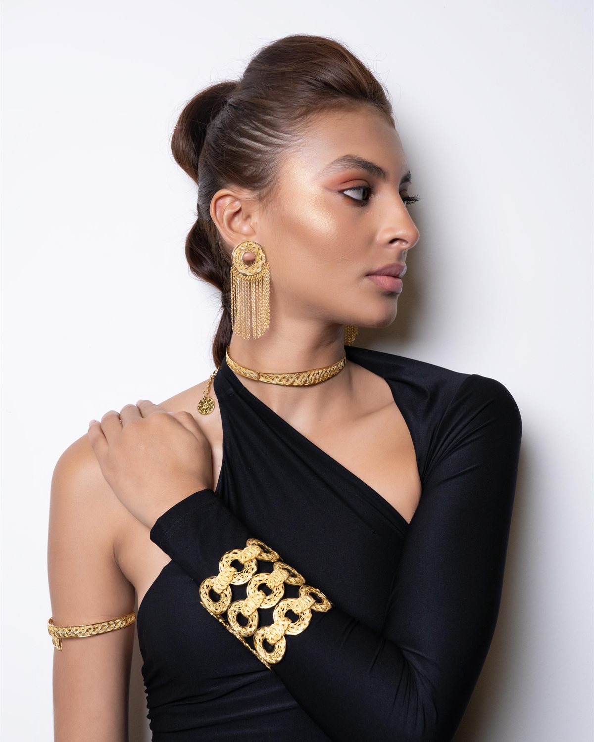 Modelo de perfil con pieza pectoral dorada geométrica y brazalete