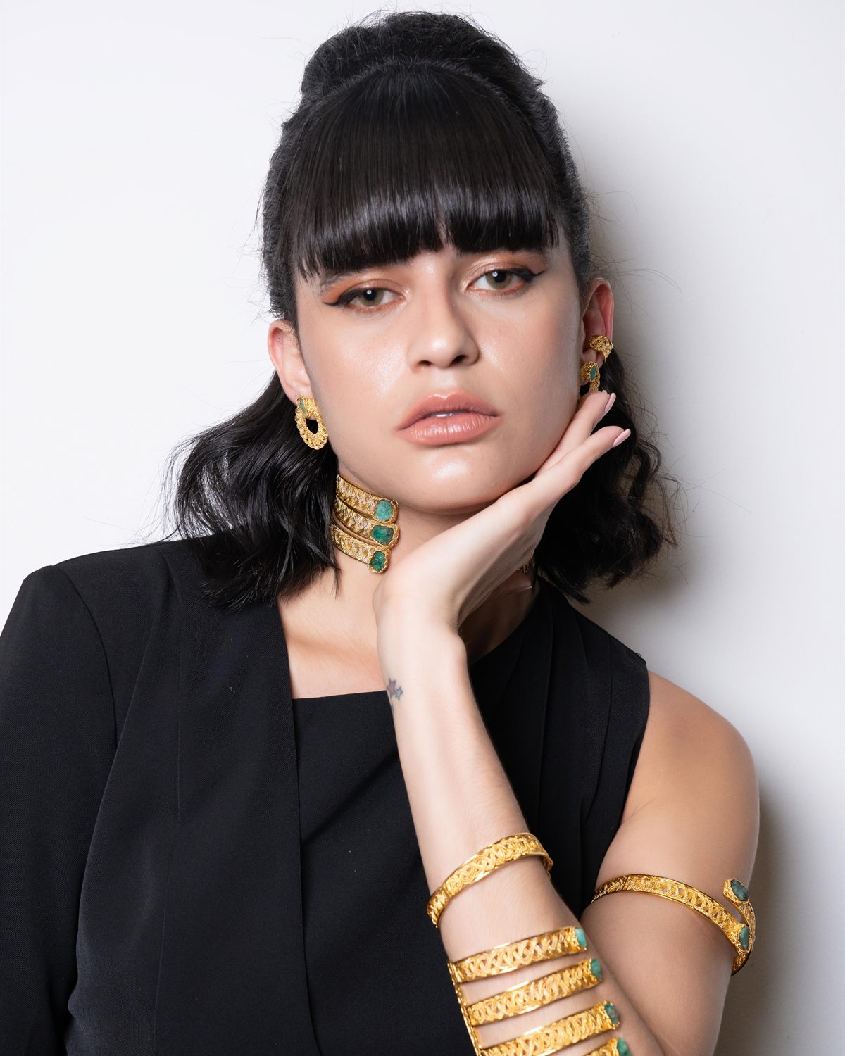 Modelo de flequillo recto con múltiples brazaletes dorados apilados