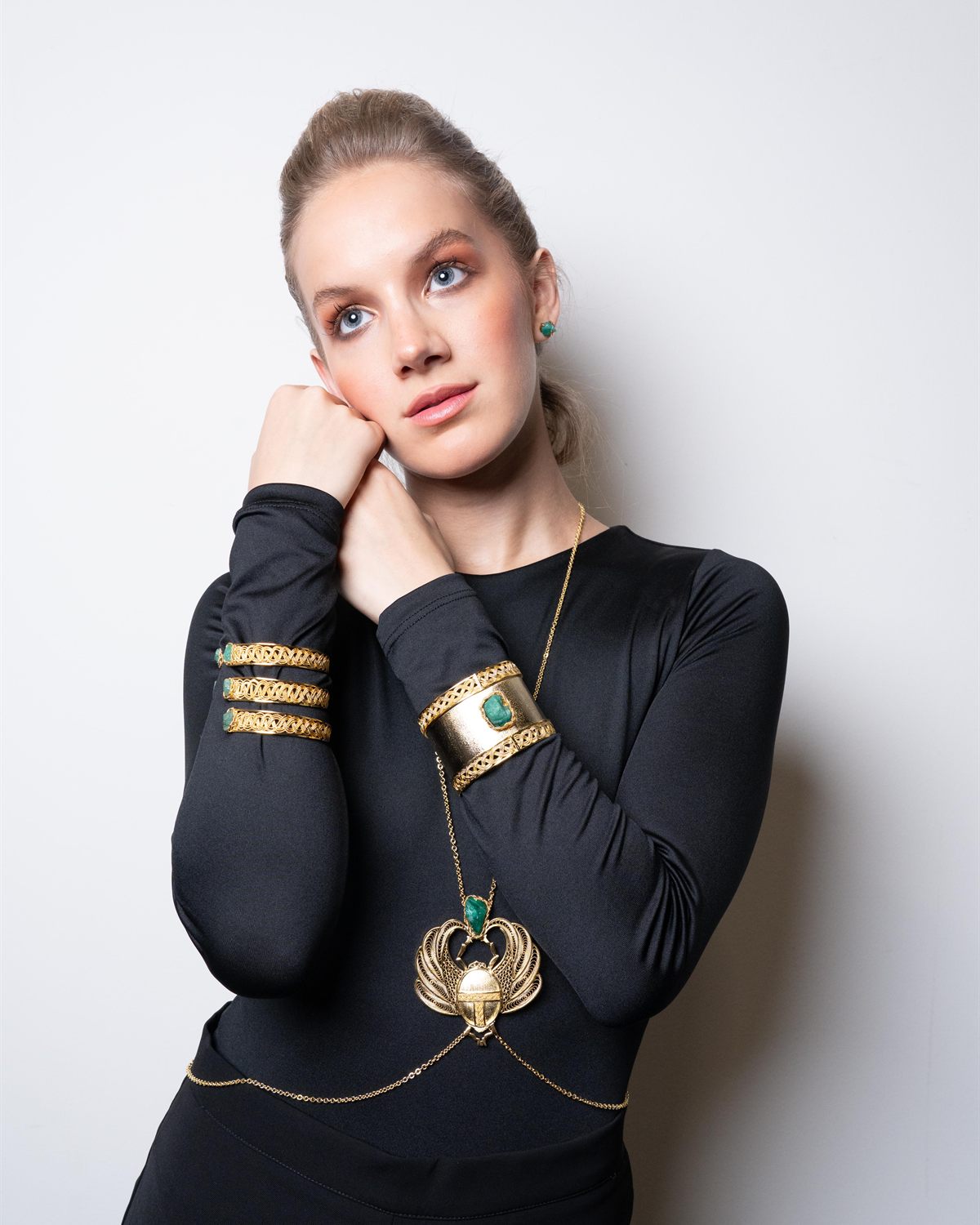 Modelo rubia con collar circular dorado y brazaletes