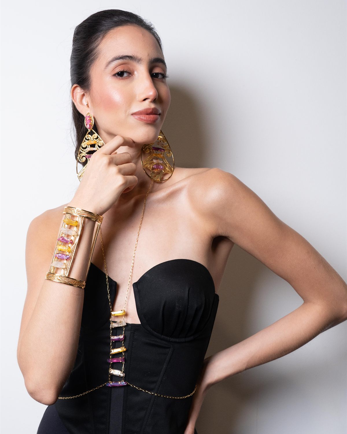 Modelo con collar dorado y mano al mentón