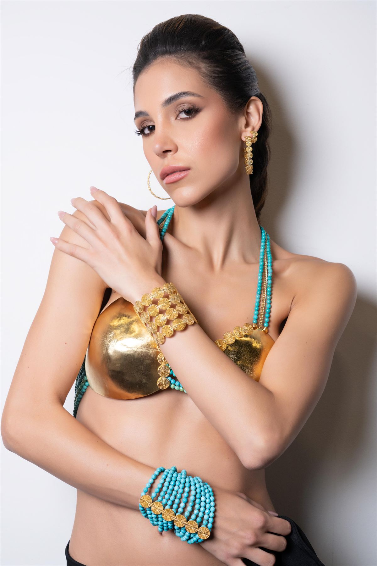 Modelo con pectoral dorado y collar de turquesas, mirada a cámara