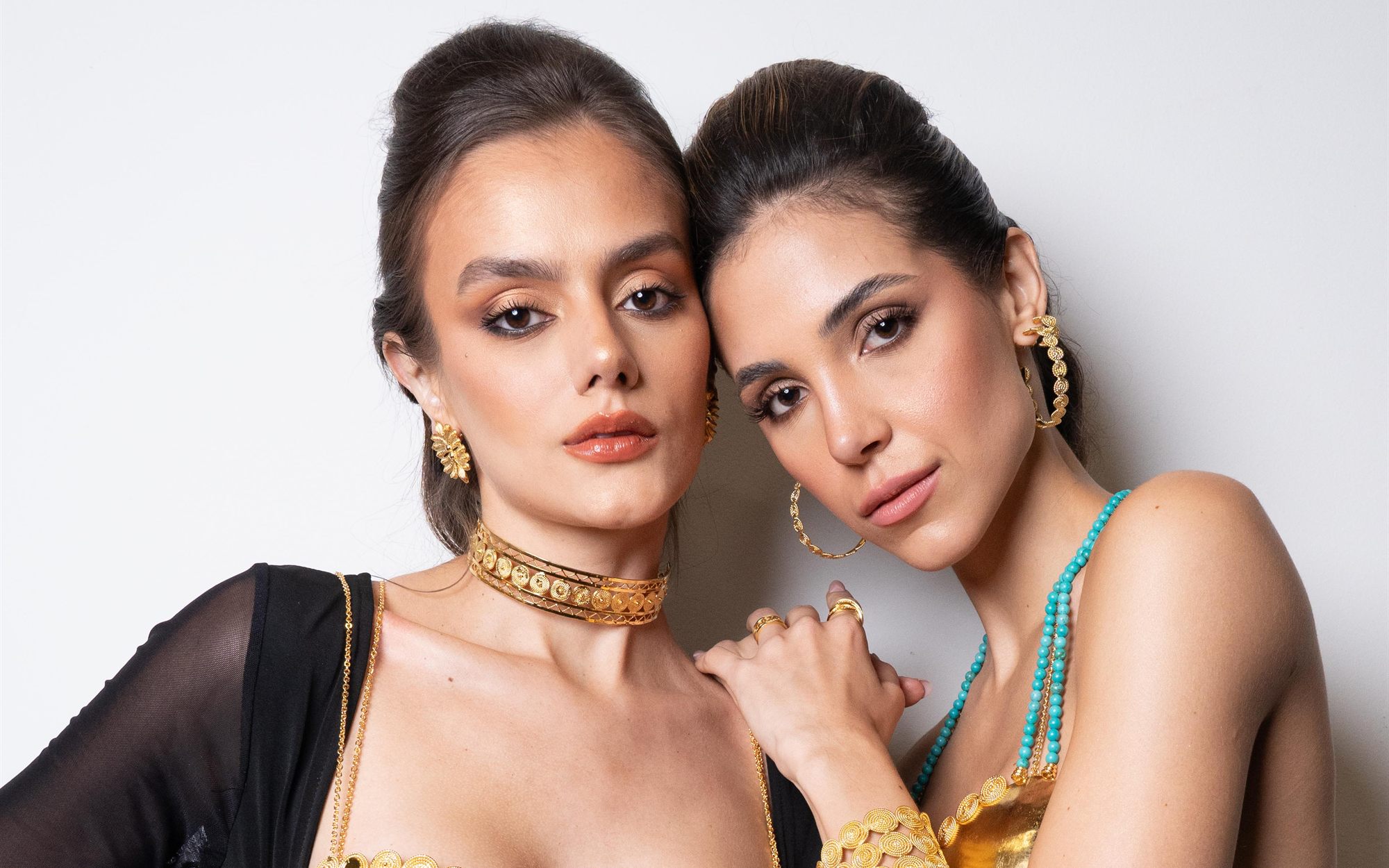 Dos modelos en primer plano con gargantillas y aretes de latón dorado