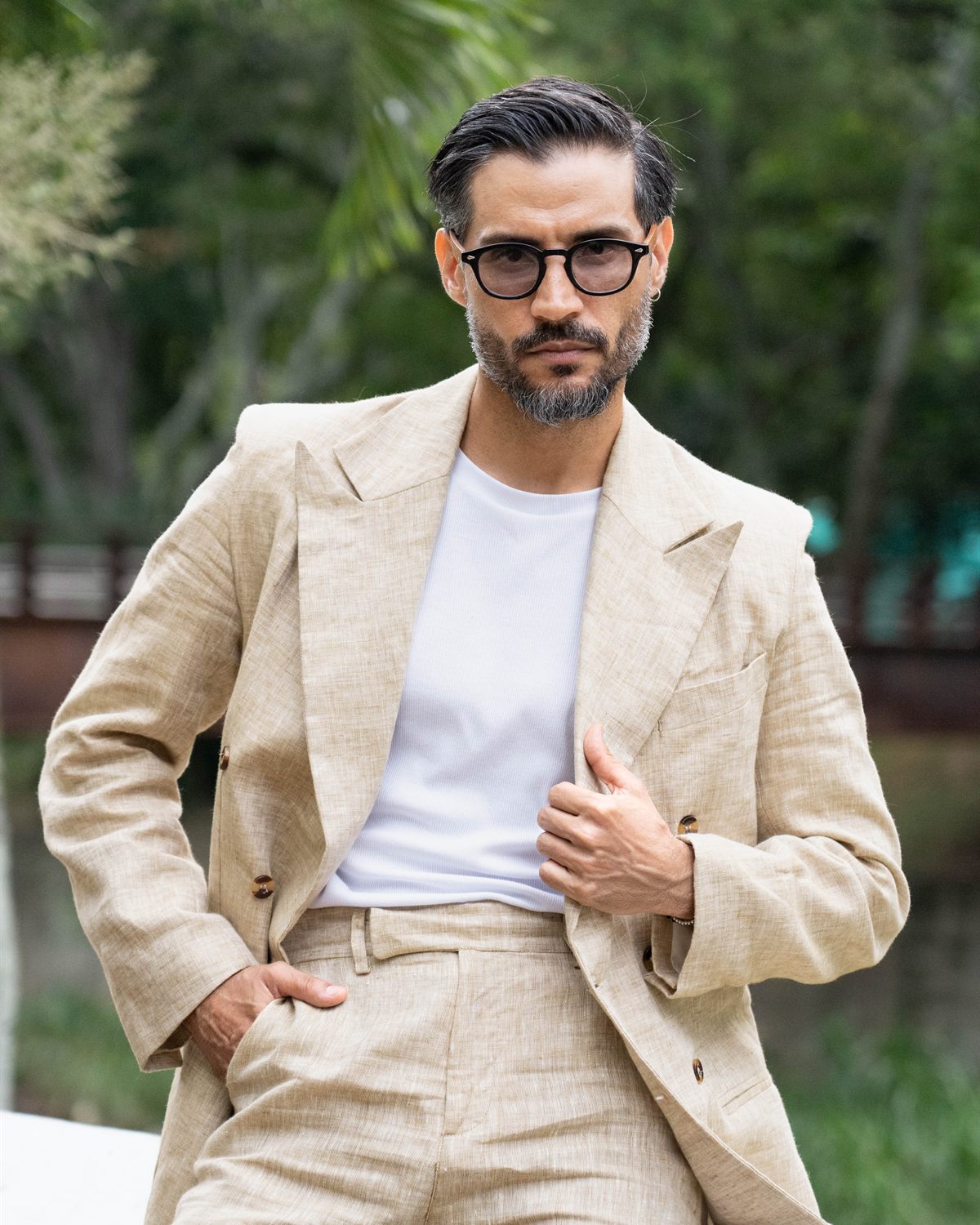 Modelo con traje de lino beige apoyado en una baranda blanca