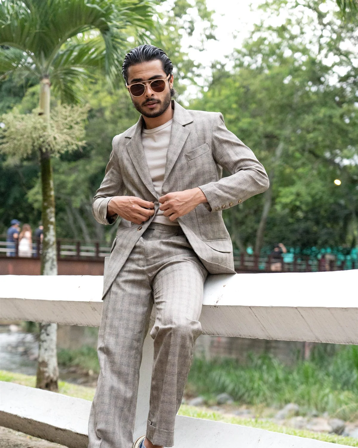 Modelo caminando con traje gris y zapatillas deportivas
