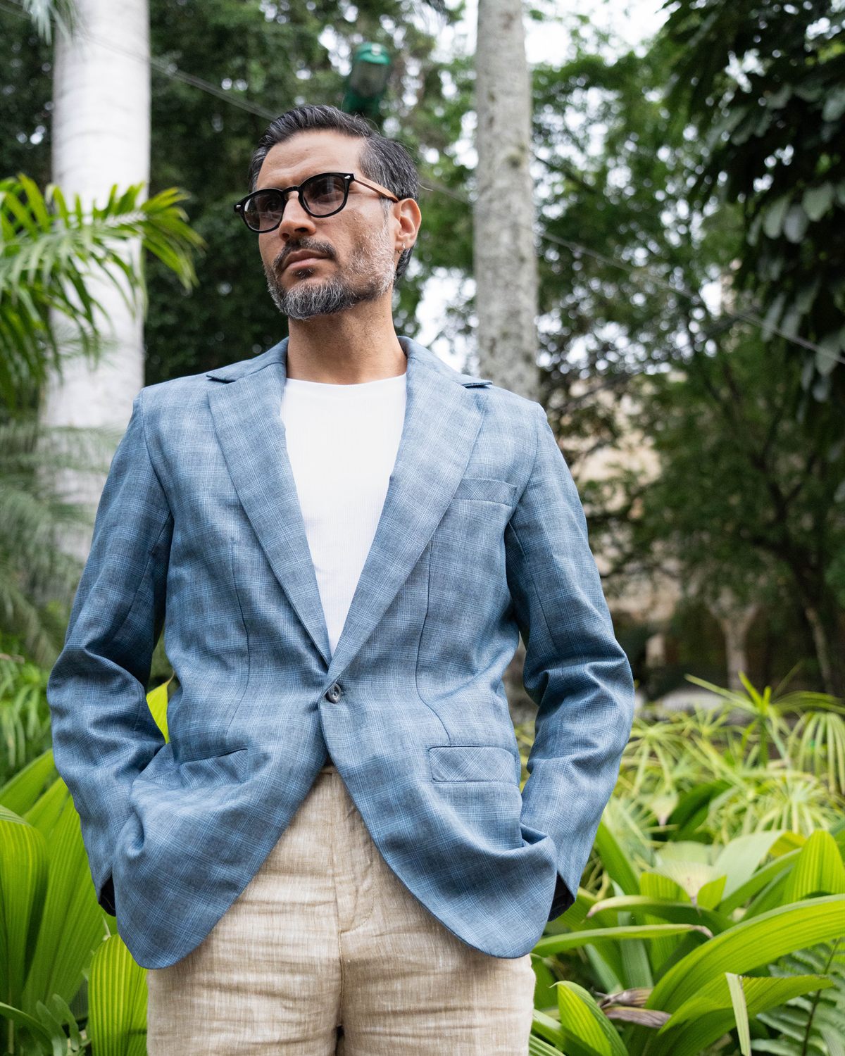 Modelo con blazer azul de cuadros entre plantas tropicales